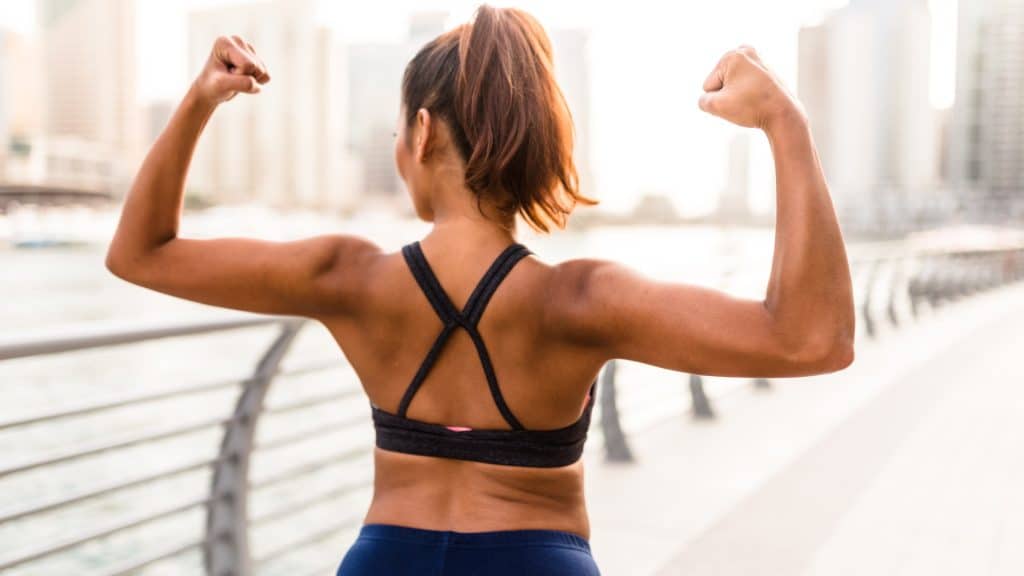 Woman flexing muscles by waterfront